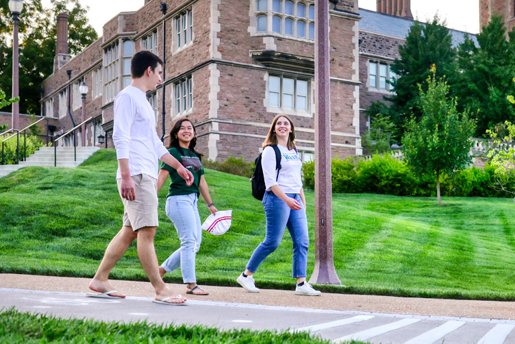 Three students walking with Brookings Hall in background