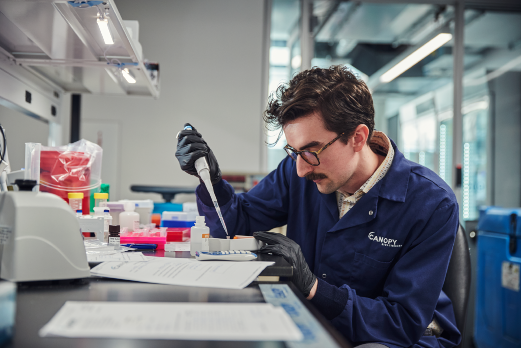 A person using a pipette in a lab setting.